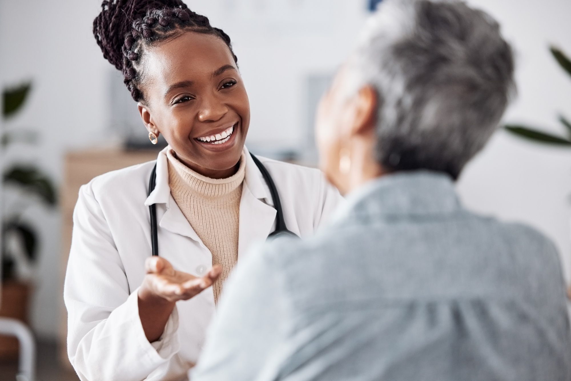 Smile, black woman or doctor consulting a patient in meeting in hospital for healthcare feedback or